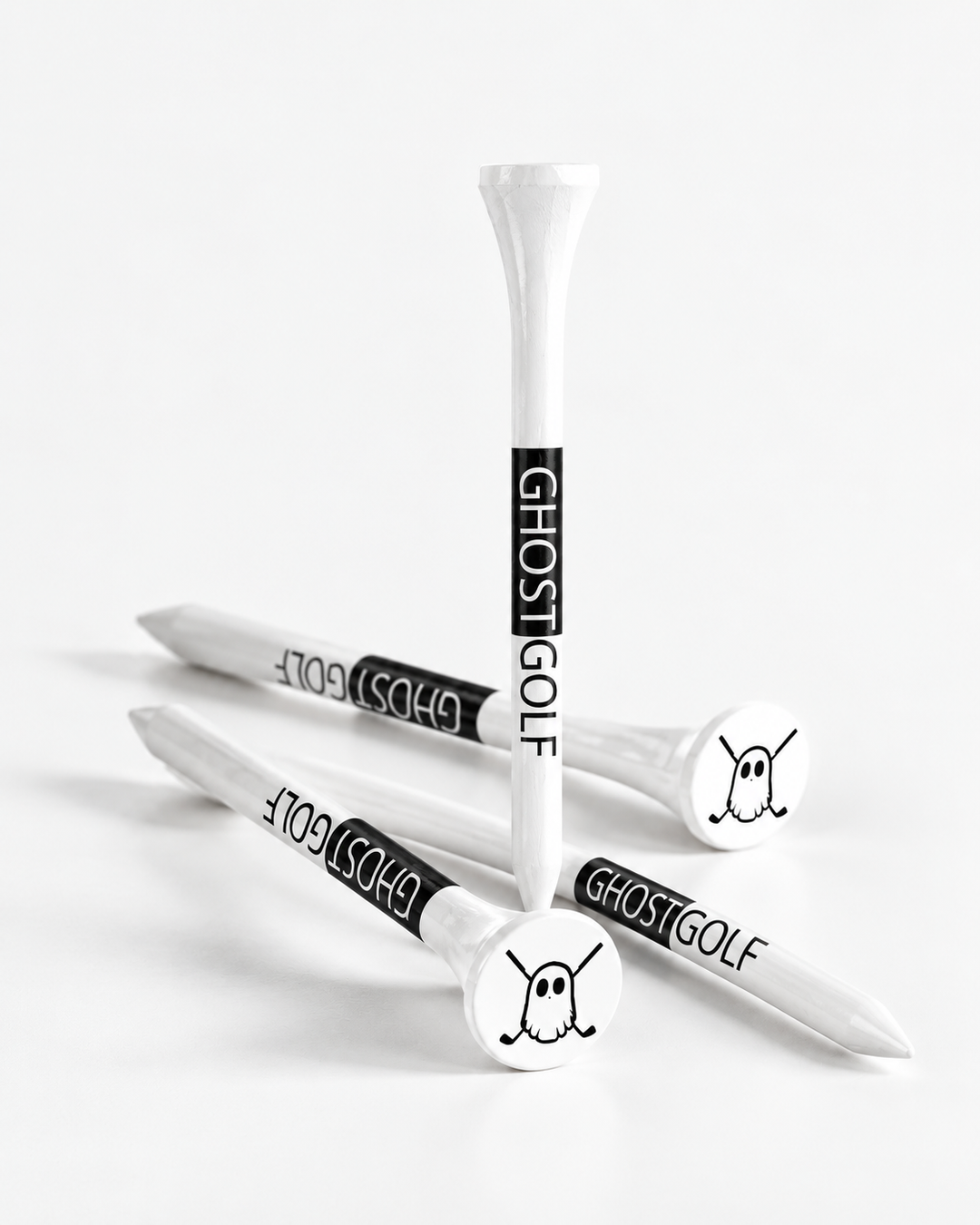 Four white golf tees with black and white 'GHOSTGOLF' branding and ghost illustrations, arranged on a clean white background.