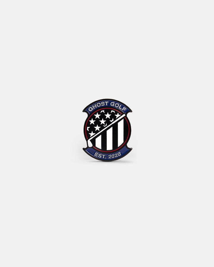 Product photo of a circular ball marker featuring a patriotic Ghost Golf emblem with stars and stripes, a golf club crossing diagonally through the center, the Ghost Golf name at the top, and “EST. 2020” at the bottom.