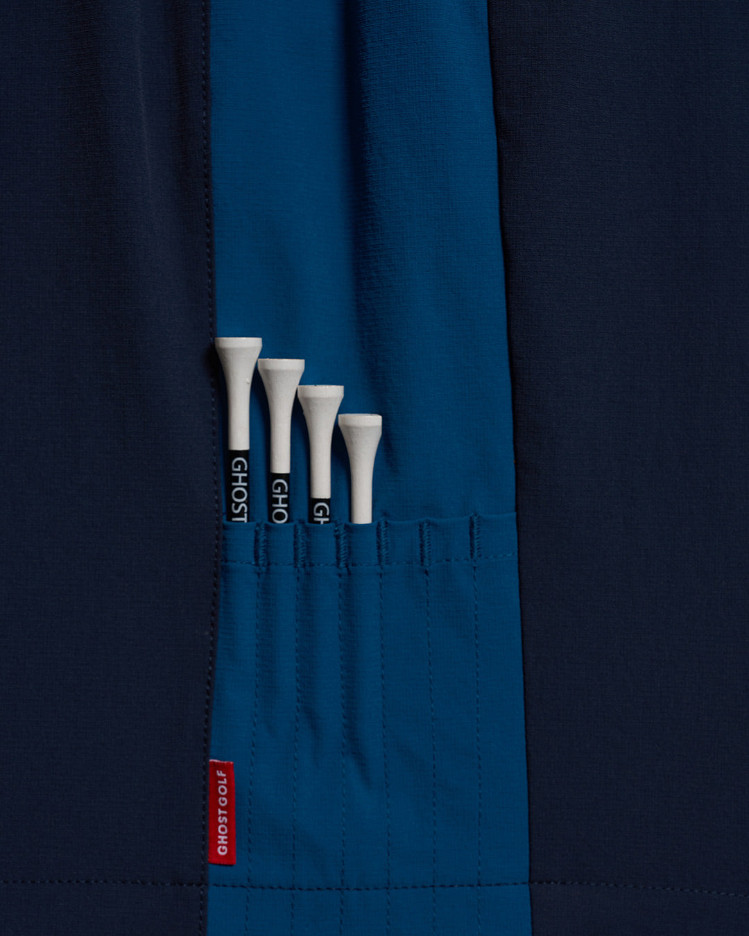 Detail Shot of Navy Fairway Windshort V2 holding golf tees #color_navy