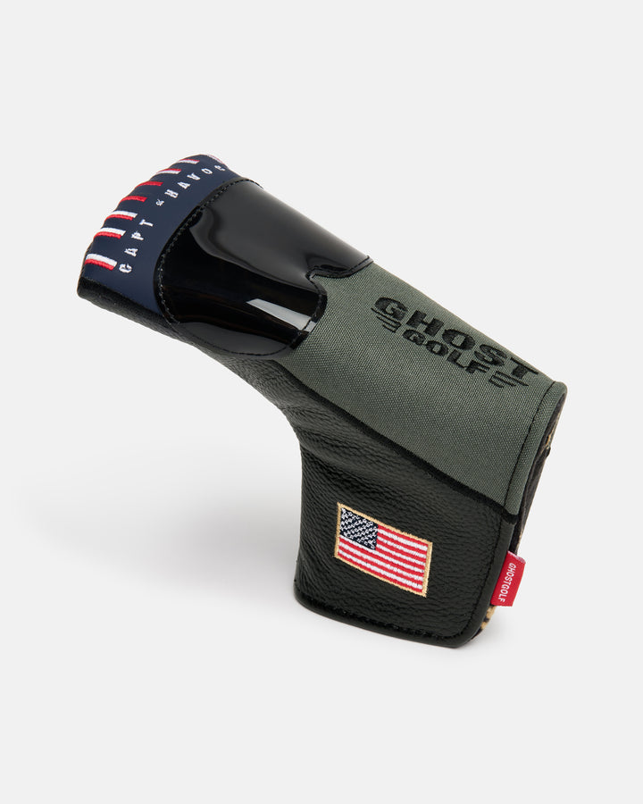 Side product shot of the G-Suit Primary Blade Putter Cover featuring an aviator helmet-inspired fighter jet design on the front, "USA" embroidery along the lower side panel, and the Ghost Golf logo embroidered on the top. The cover also showcases Capt Havoc embroidery, highlighting the military aviation-inspired theme. Angled profile view emphasizing the premium materials, detailed embroidery, patriotic elements, and signature Ghost Golf craftsmanship.