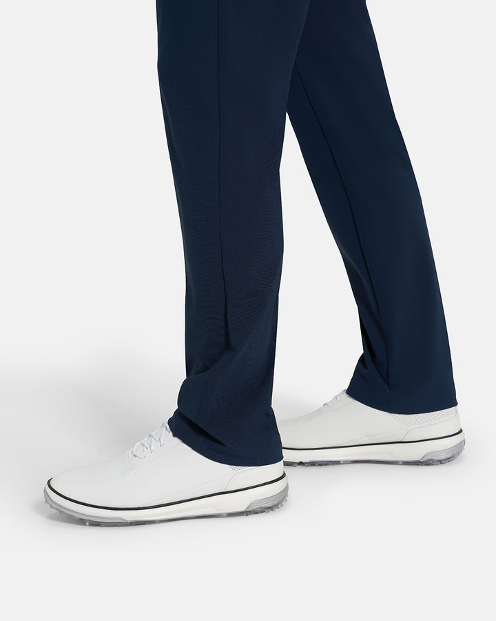Bottom Closeup Side View of Navy Ghost Golf Core 5 Pocket Pant on White male Model #color_navy
