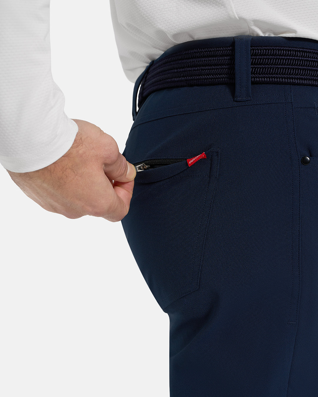 Closeup Side View of Navy Ghost Golf Core 5 Pocket Pant on White Male Model with hand pulling back pocket zipper #color_navy