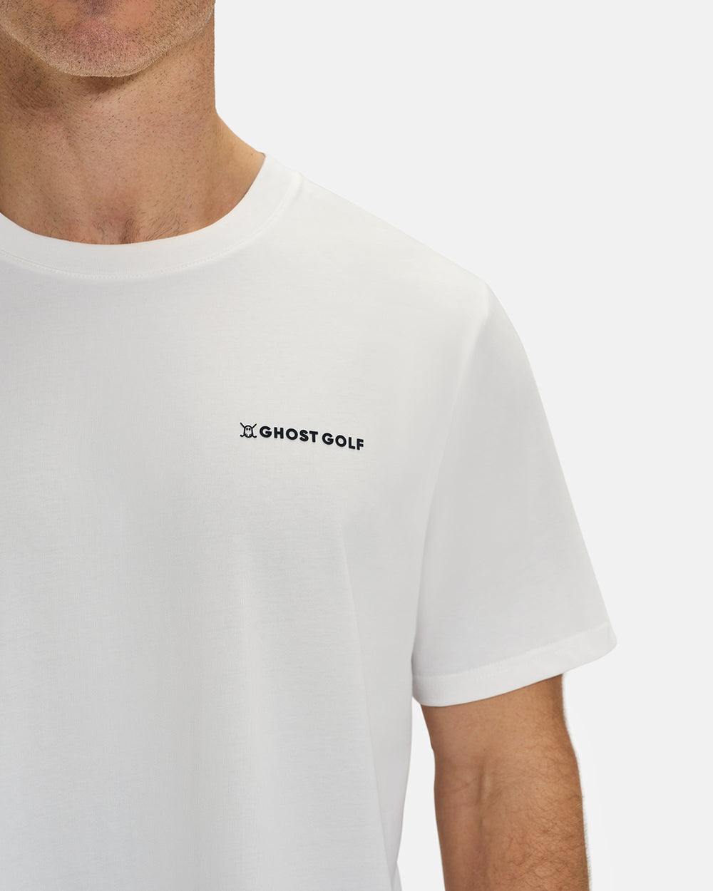 Front Closeup View of Optic White Ghost Golf Core Logo Tee on White Male Model #color_white