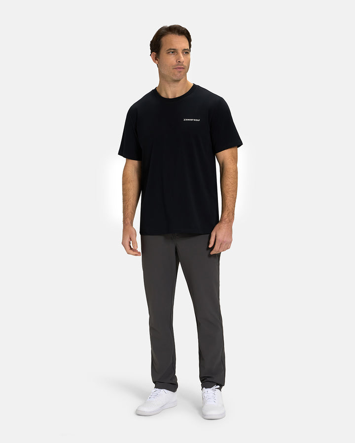 Full Body View of Black Ghost Golf Core Logo Tee on White Male Model wearing grey pants and white shoes #color_black