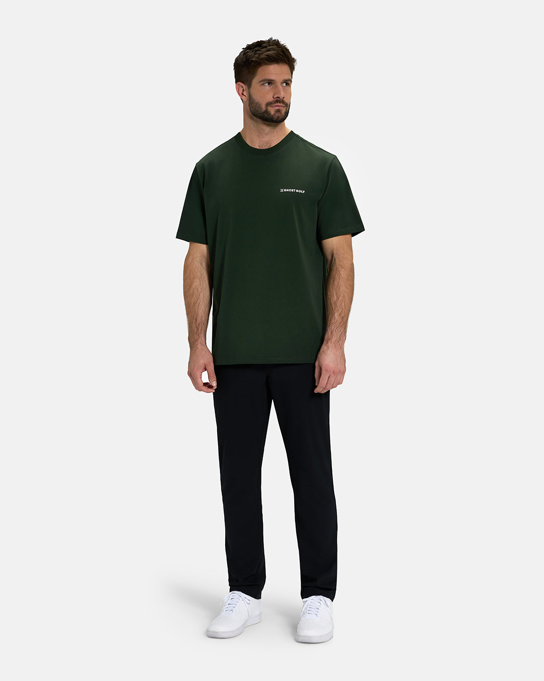 Full Body View of Forest Green Ghost Golf Core Logo Tee on White Male Model wearing black pants and white shoes #color_forest-green