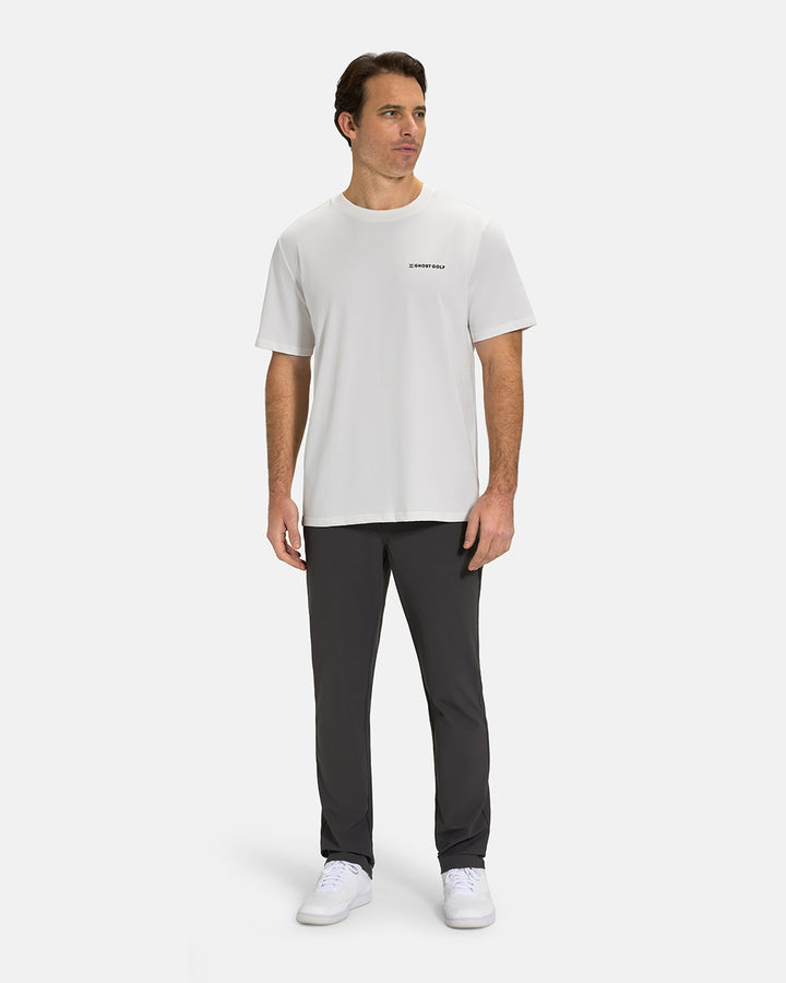 Full Body View of Optic-White Ghost Golf Core Logo Tee on White Male Model wearing grey pants and white shoes#color_white