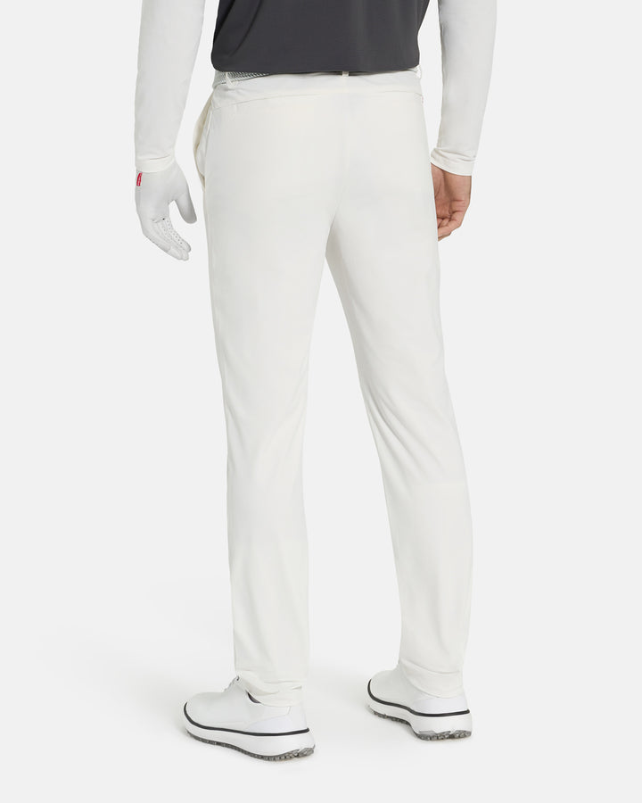 Back View of White Ghost Golf Core Pant on White Male Model wearing a tucked in grey polo and white shoes #color_white