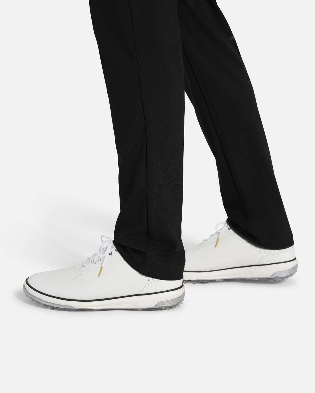 Bottom Closeup Side View of Black Ghost Golf Core Pant on White Male Model with white shoes #color_black