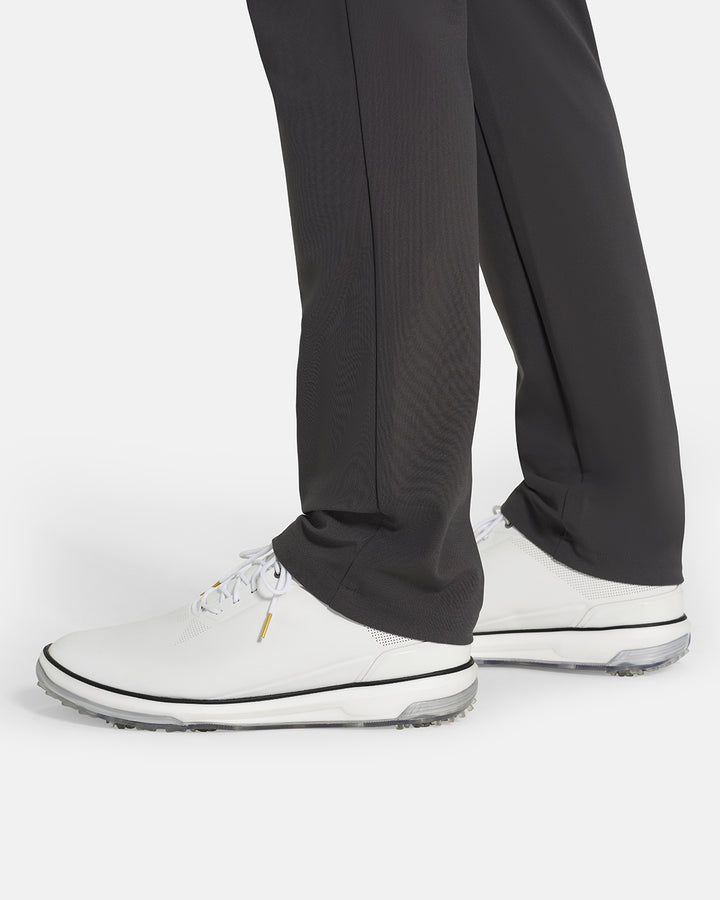 Bottom Closeup Side View of Iron Grey Ghost Golf Core Pant on White Male Model with white shoes #color_iron-grey