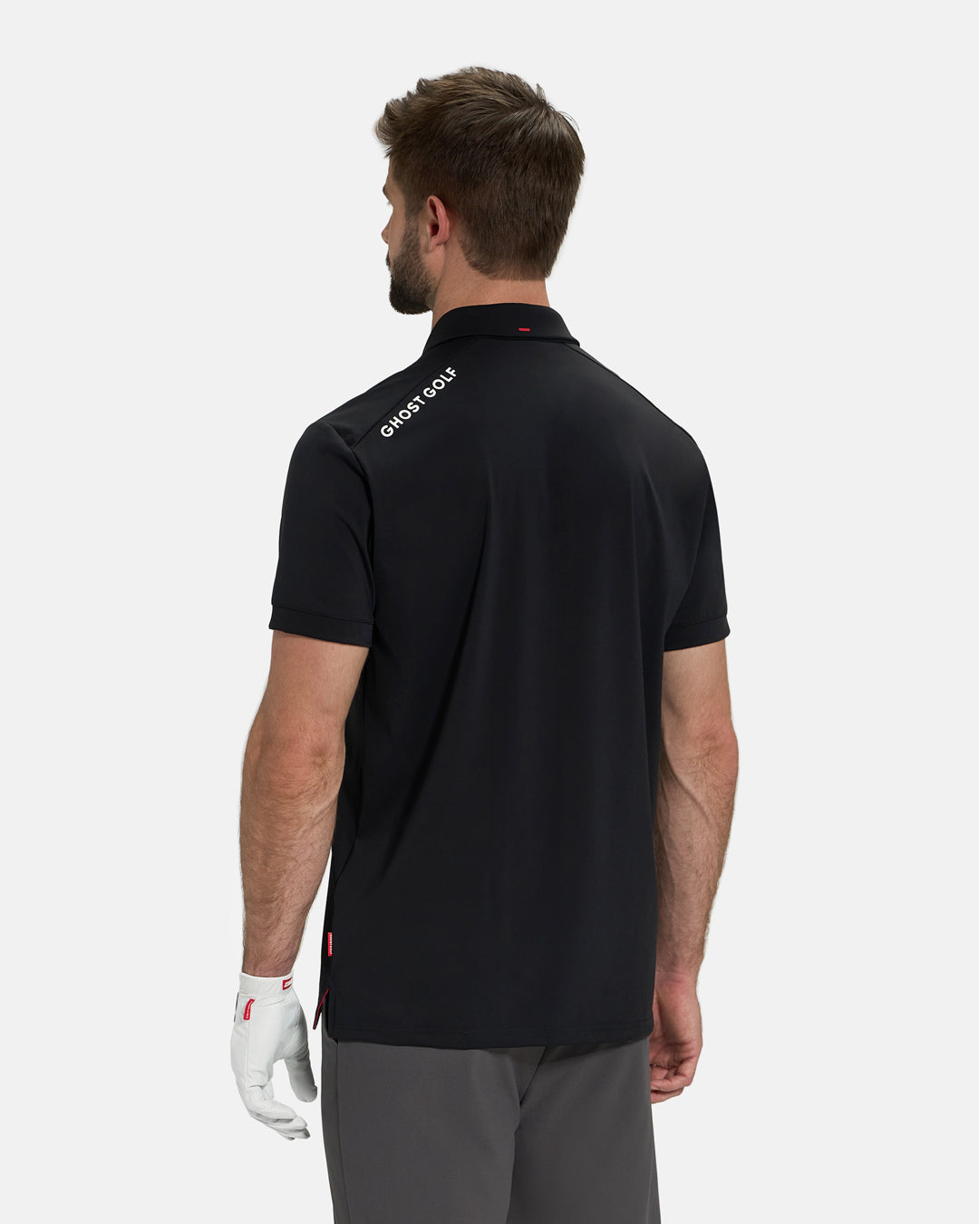 Back View of Black Ghost Golf Core Polo Untucked on White Male Model with Ghost Golf logo on back #color_black