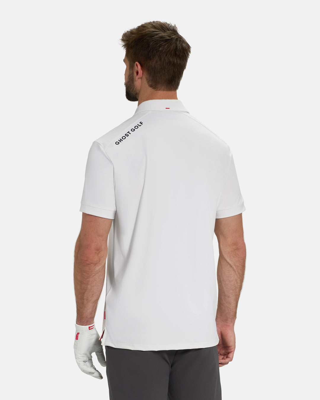 Back View of Optic White Ghost Golf Core Polo Untucked on White Male Model with Ghost Golf logo on back #color_white