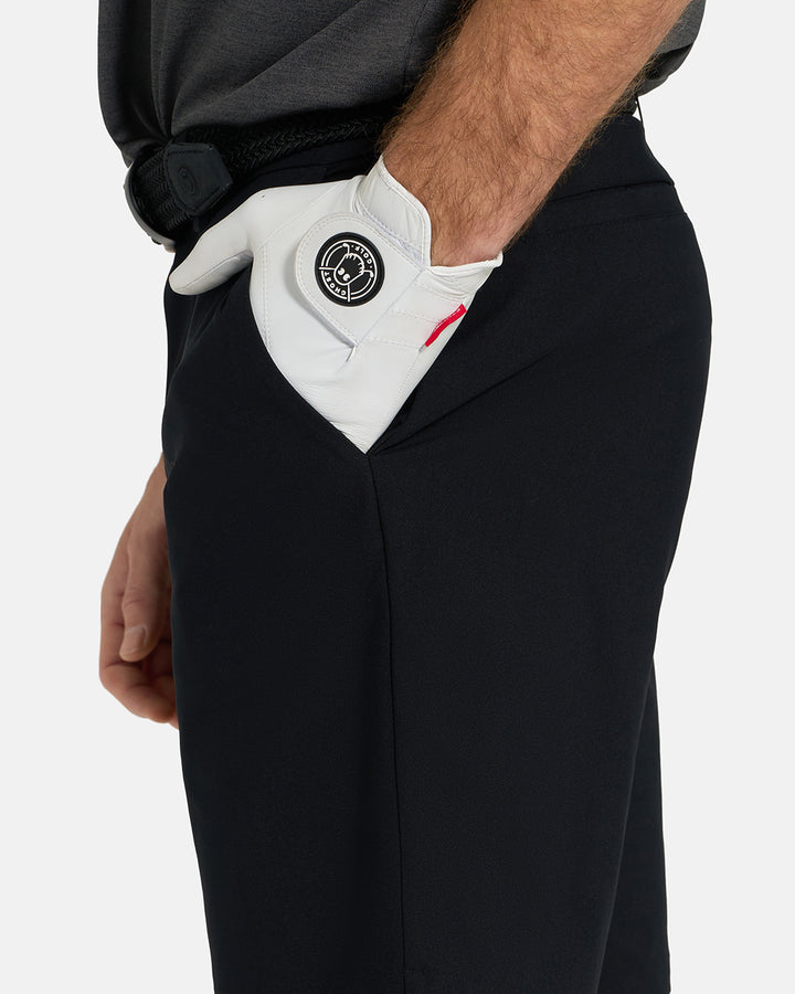 Side Closeup View of Black Ghost Golf Core Short on White Male Model with hand in pocket #color_black