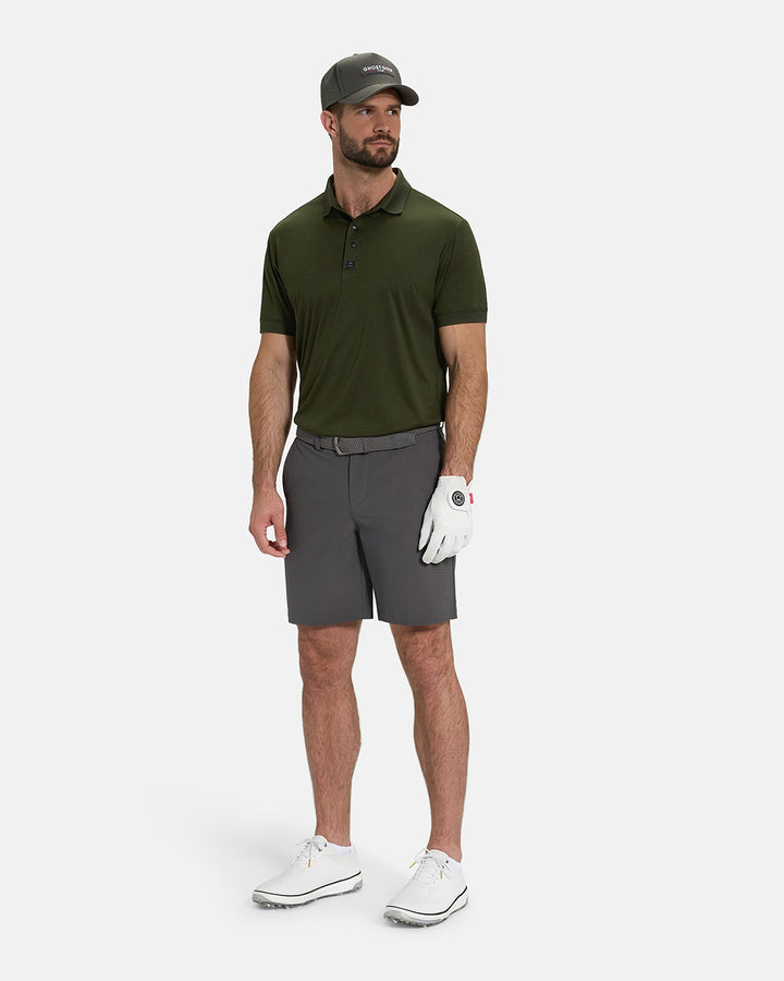 Full Body View of Forest Green Ghost Golf Marled Core Polo Tucked on White Male Model wearing grey shorts white gloves grey belt white shoes and grey hat #color_forest-green