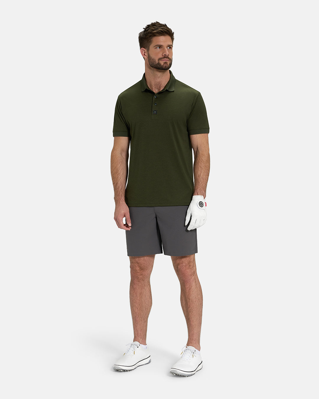Full Body View of Forest Green Ghost Golf Marled Core Polo Untucked on White Male Model wearing grey shorts white gloves and white shoes #color_forest-green
