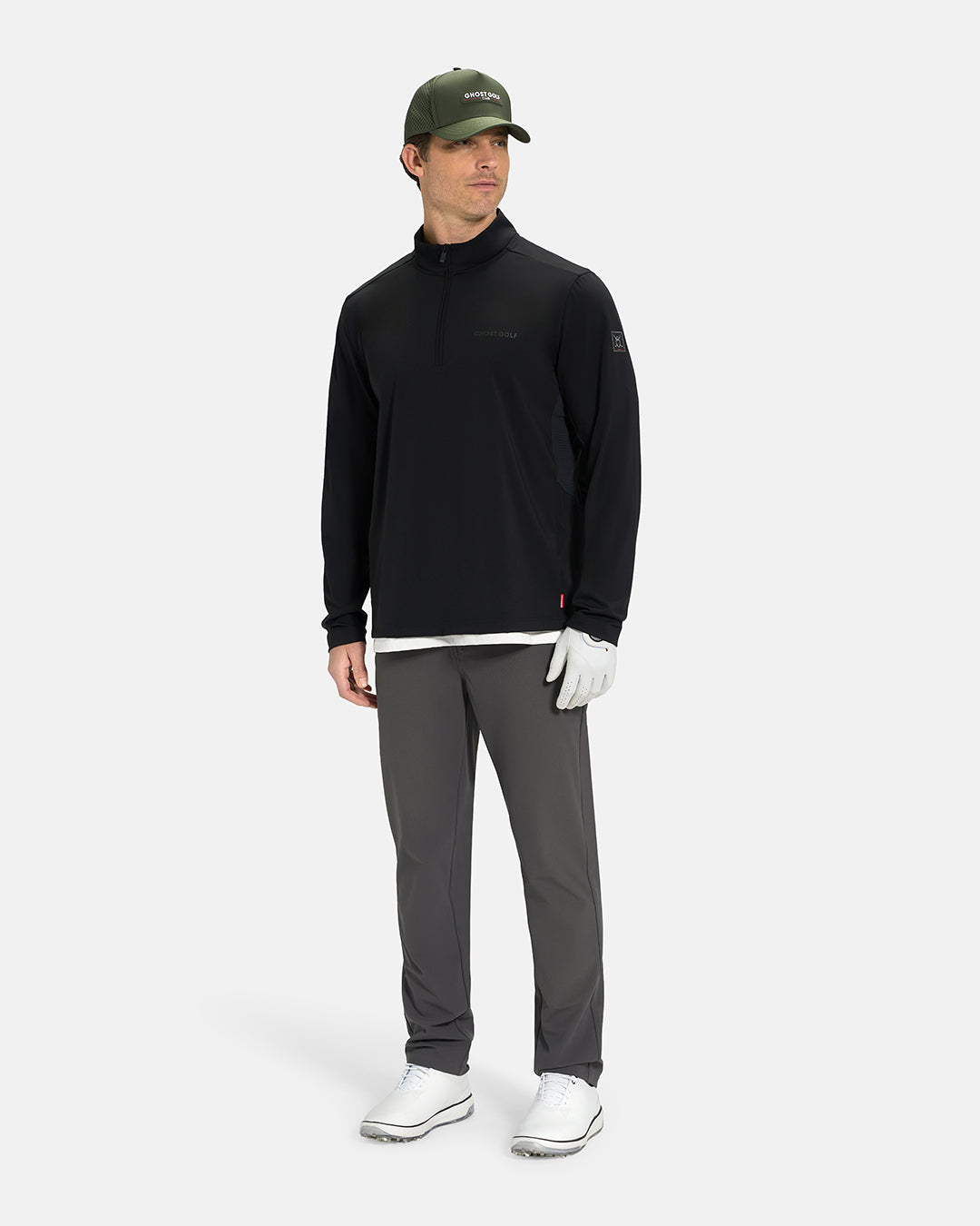 Full Body View of Black Ghost Golf Quarter Zip Mock Jacket on White Male Model wearing grey pants white glove forest green hat white shoes and white tee #color_black