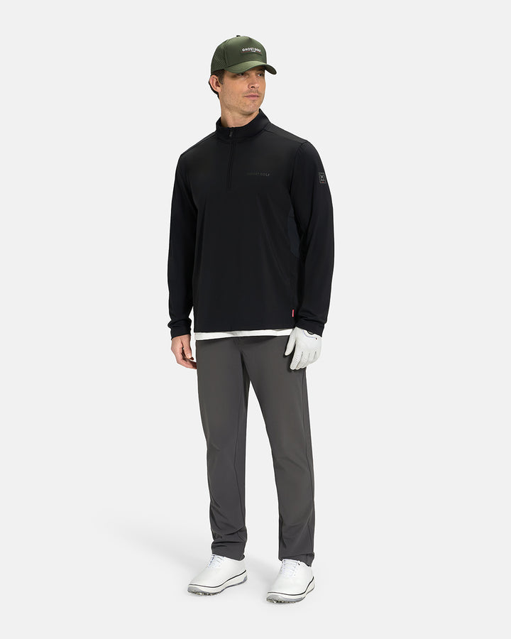 Full Body View of Black Ghost Golf Quarter Zip Mock Jacket on White Male Model wearing grey pants white glove forest green hat white shoes and white tee #color_black