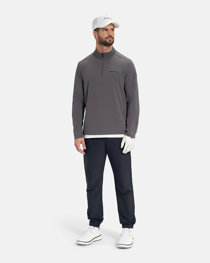 Full Body View of Iron Grey Ghost Golf Quarter Zip Mock Jacket on White Male Model wearing navy pants white glove white hat white shoes and white tee #color_iron-grey