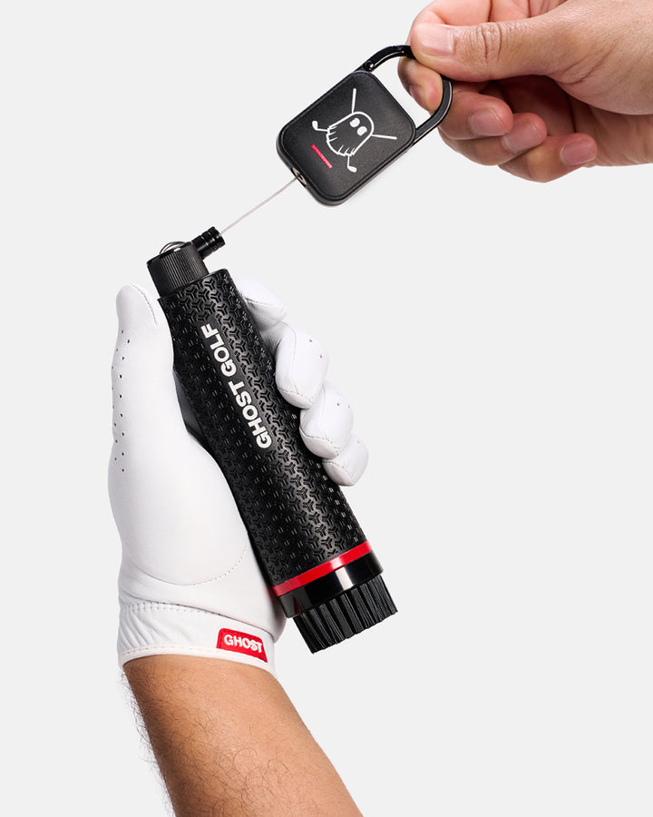 Golfer with White Glove holding a Black Ghost Golf club and shoe cleaning brush with a magnetic back and Carabiner attached to it #color_black