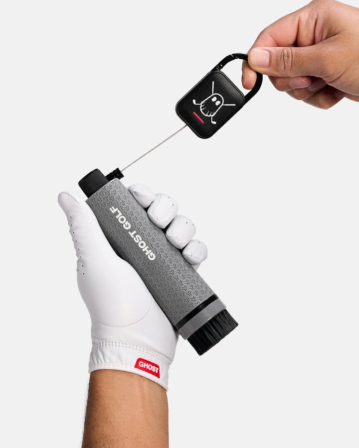 Golfer with White Glove holding a Grey Ghost Golf club and shoe cleaning brush with a magnetic back and Carabiner attached to it #color_grey