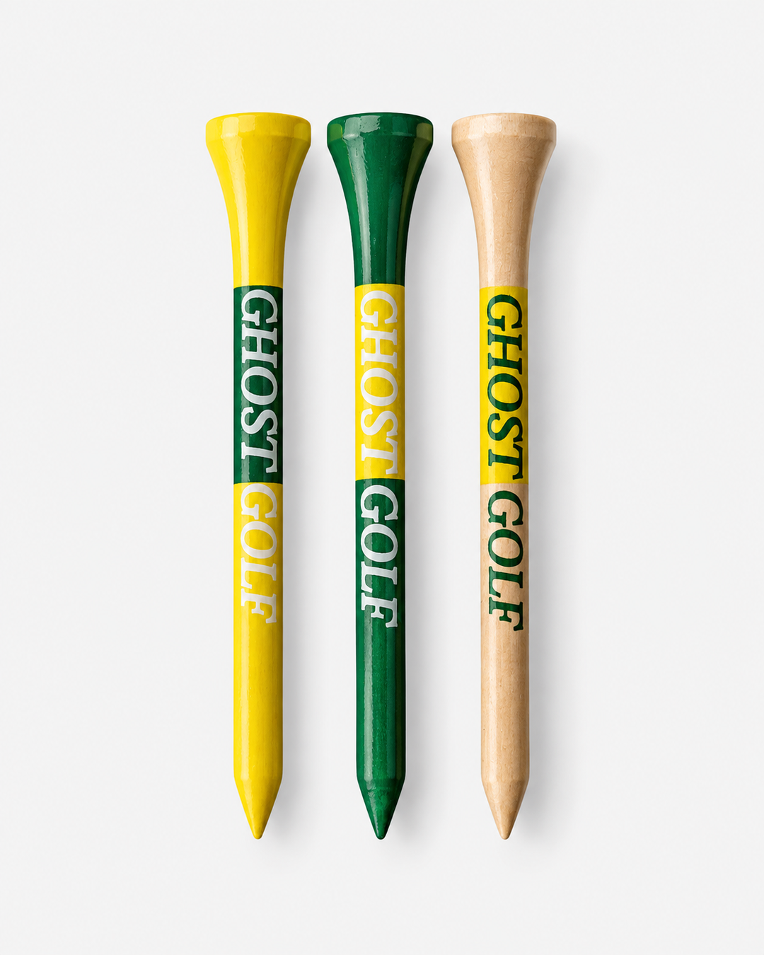 Three golf tees with 'GHOST GOLF' branding, shown vertically against a light gray background. The left tee is yellow and green, the middle tee is green and yellow, and the right tee is natural wood with a yellow and green label.