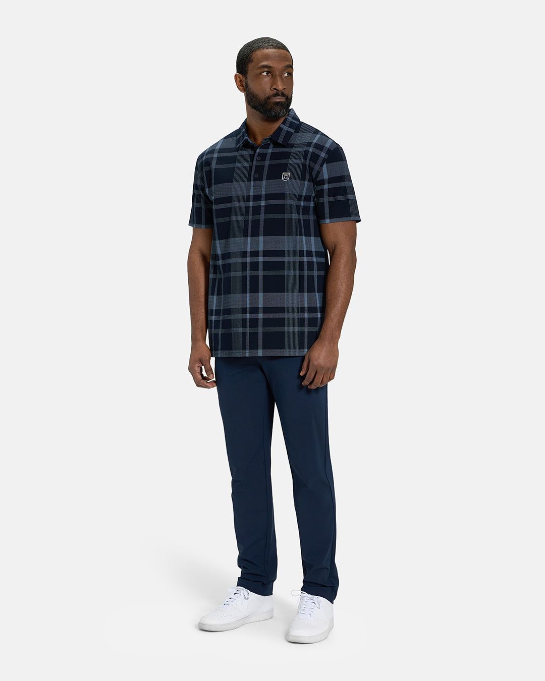 Full Body Front View of Navy Spectator Plaid Polo on Black Male Model wearing navy pants and white shoes #color_navy