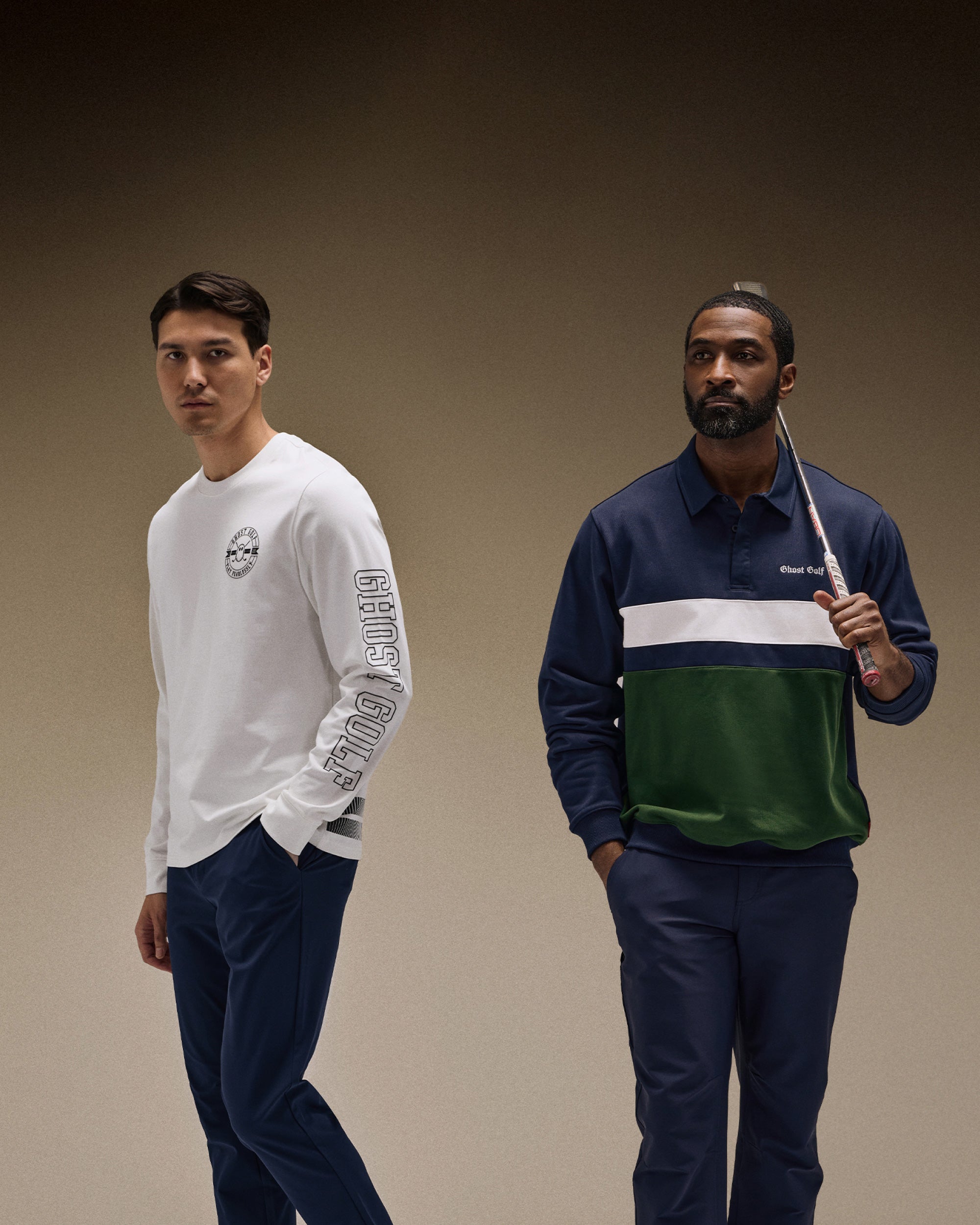 Asian and Black male models photographed in a brown studio setting. The Asian model wears a white long-sleeve tee paired with navy pants. The Black model wears a navy long-sleeve polo and matching pants, holding a golf club.