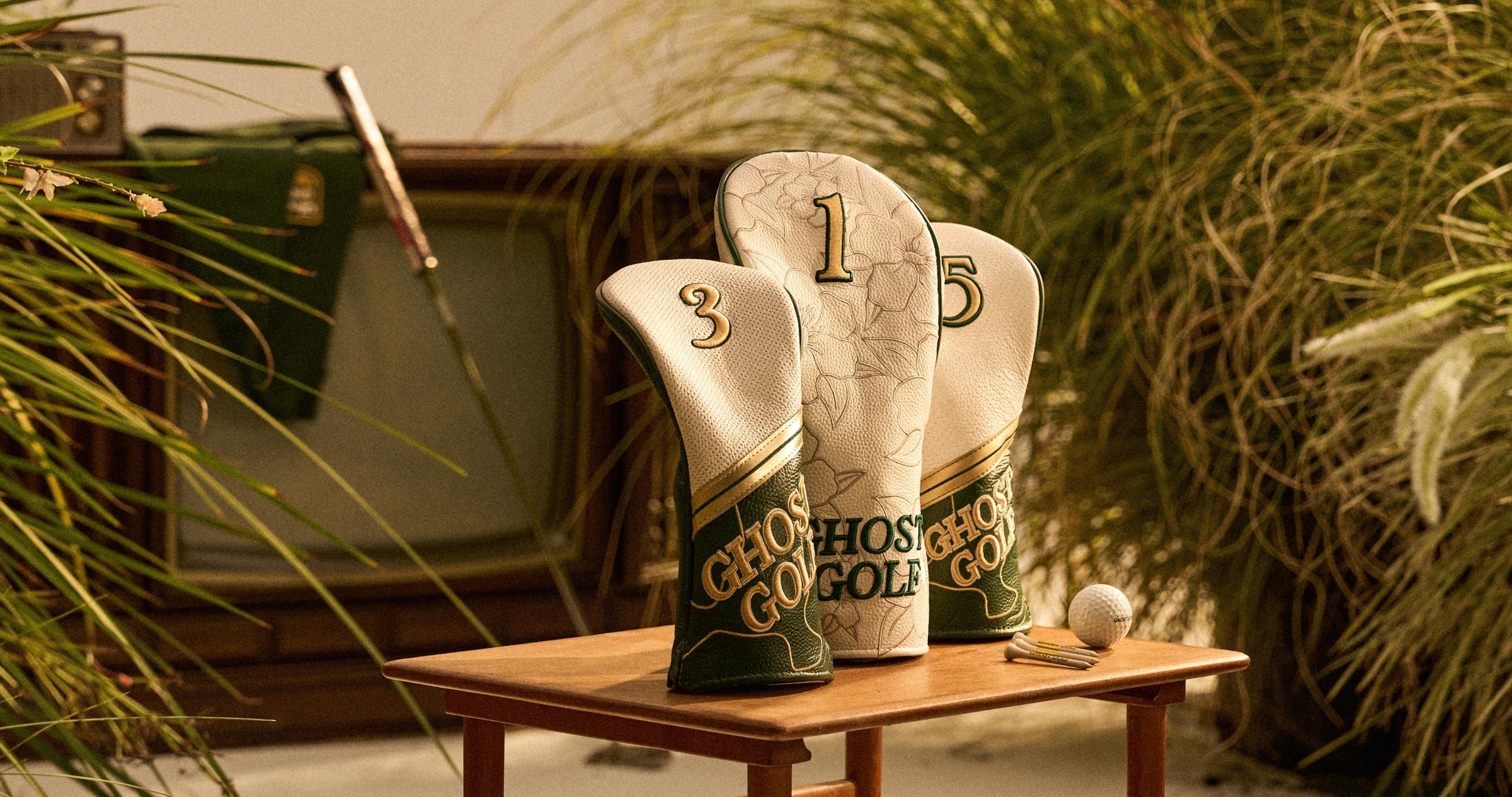 Leather Head Covers on a table with tees and golf ball in a grassy studio setting