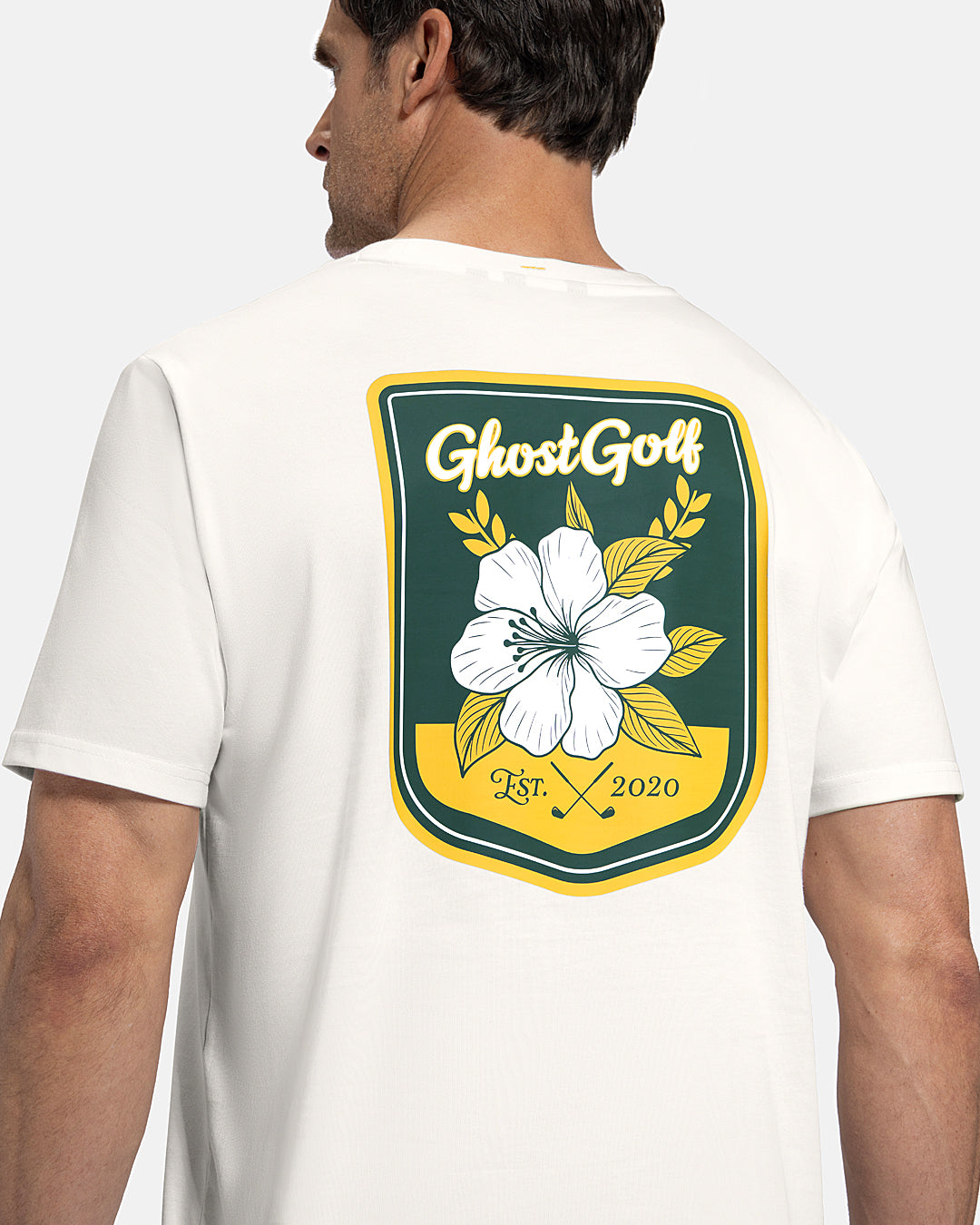Closeup Back View of White Patrons Azalea Badge Tee on white male model showing ghost golf graphic hit #color_white