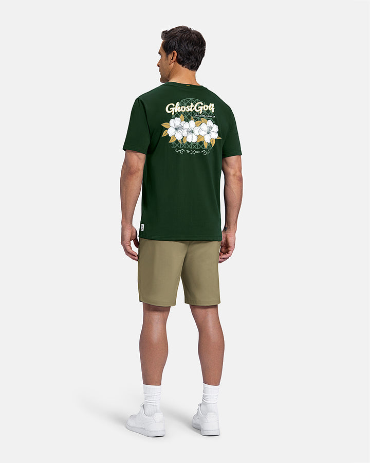 Full Body Back View of Bogey Green Patrons Azalea Tee on white male model wearing beige shorts and white shoes #color_bogey-green