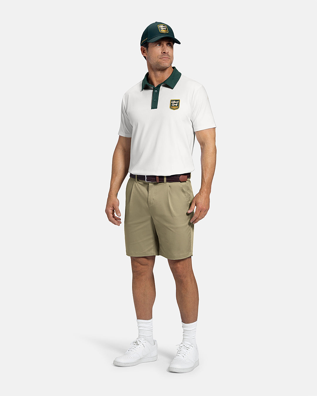 Man wearing a beige polo shirt, khaki shorts, white sneakers, and a green cap on a white background #color_cream-white