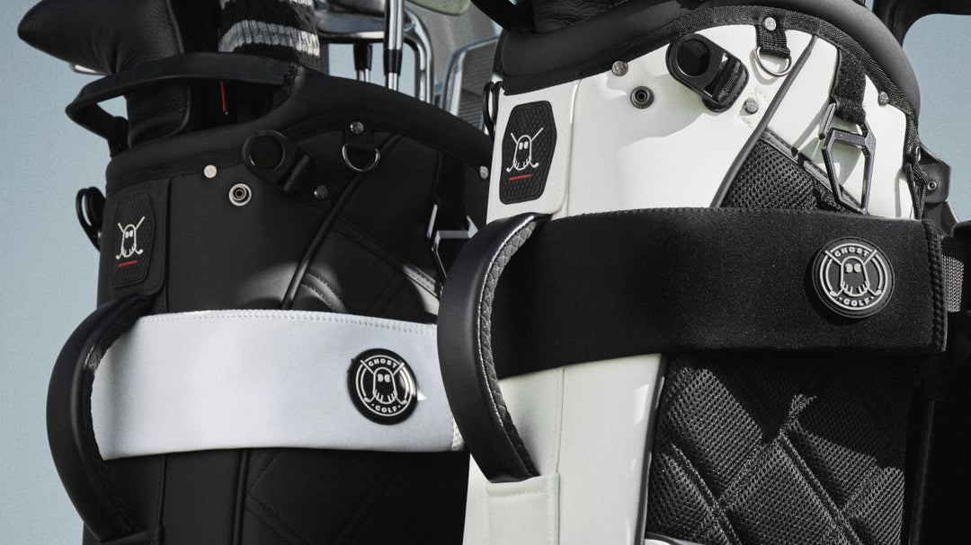 Closeup ifestyle image of one white and one black cart strap sleeves wrapped around two golf stand bags, featuring Ghost Golf branding on both the bags and strap sleeves.