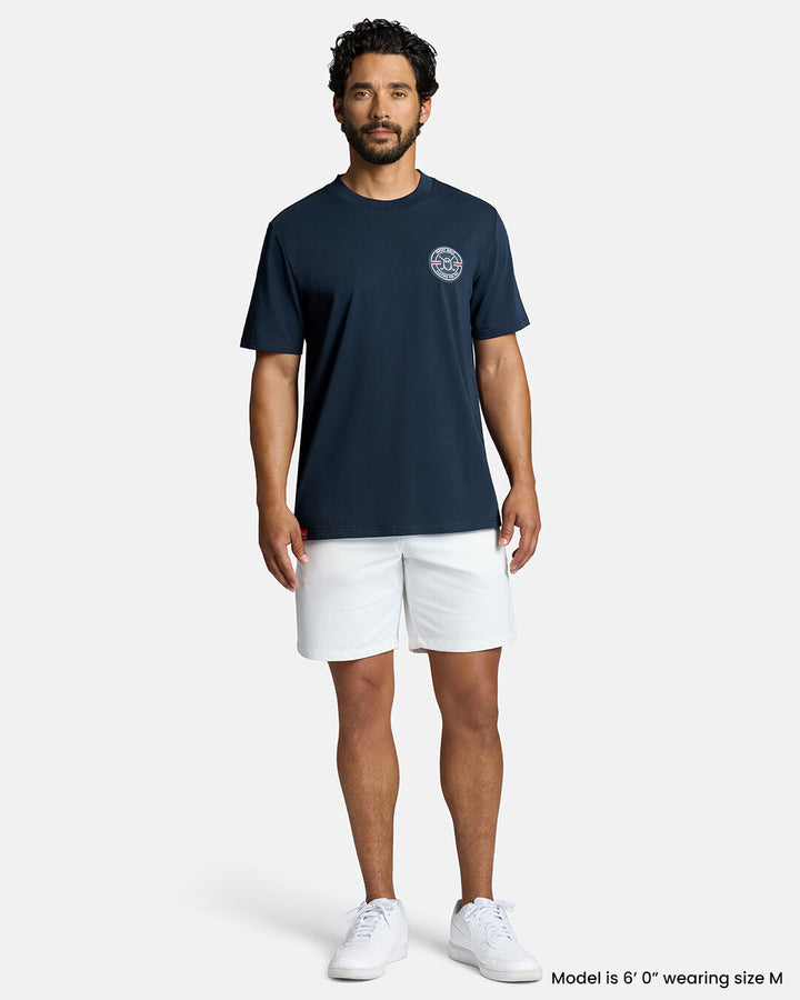 Full Body Front Shot of White Male Model Wearing Dark Navy Qualifier Fore Par Tee with white shorts and white shoes. #color_dark-navy
