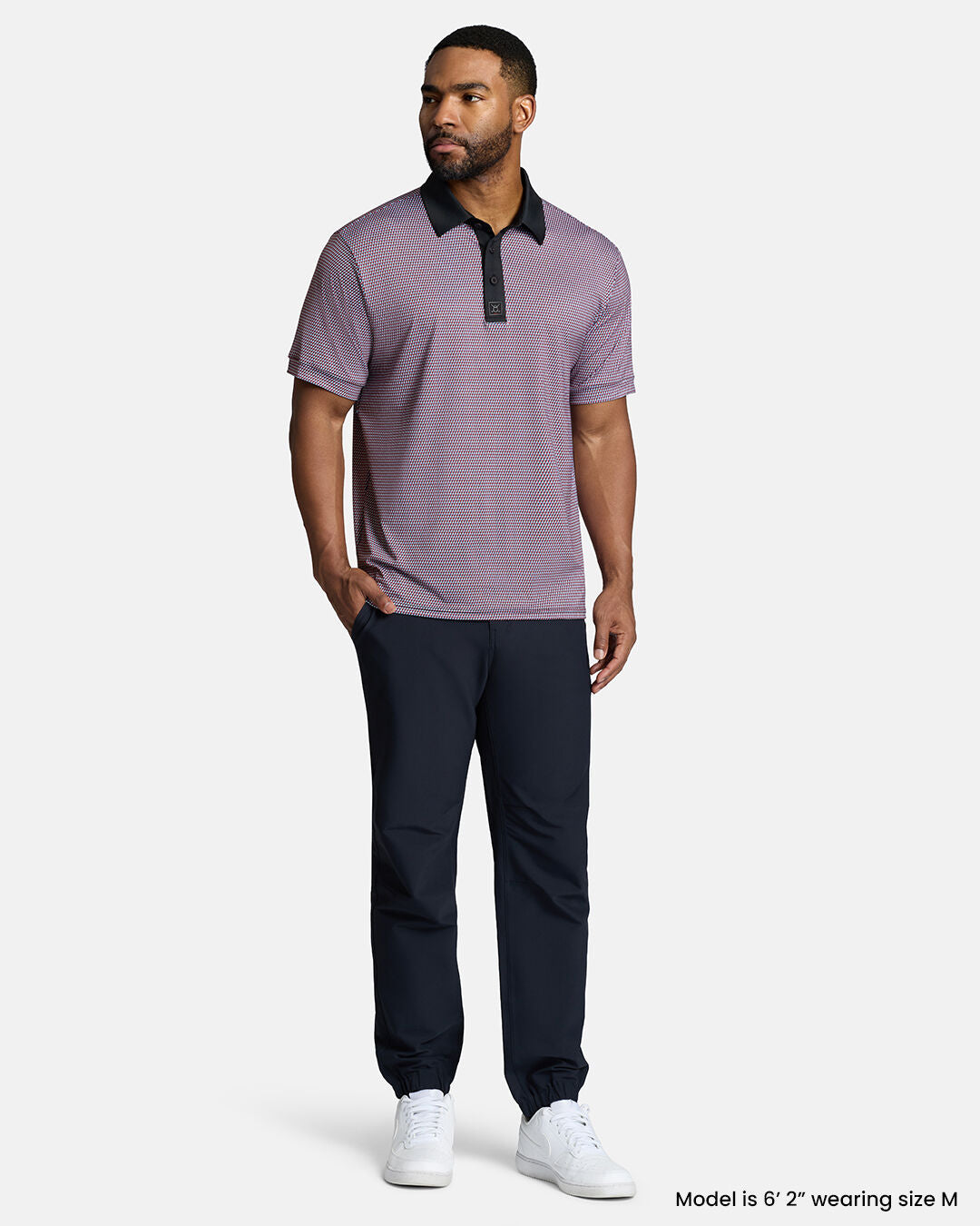 Full Body Front Shot of Black Male Model Wearing Red Qualifier Diamond Polo with navy pants and white shoes. Polo is untucked. #color_red