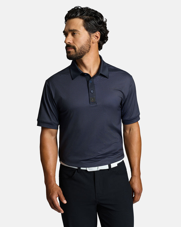 Top Front Shot of White Male Model Wearing Dark Navy Qualifier Grid Polo with polo tucked in black pants wearing white belt #color_dark-navy