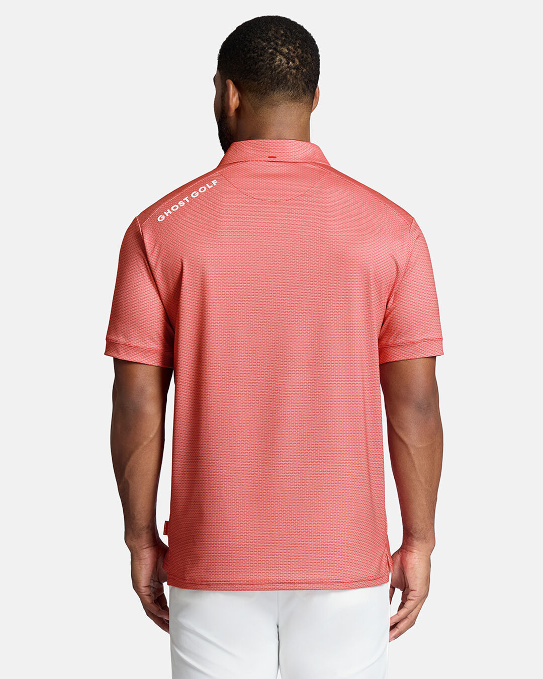 Top Back Shot of Black Male Model Wearing Red Qualifier Grid Polo untucked with ghost golf hit on back left shoulder wearing white pants #color_red