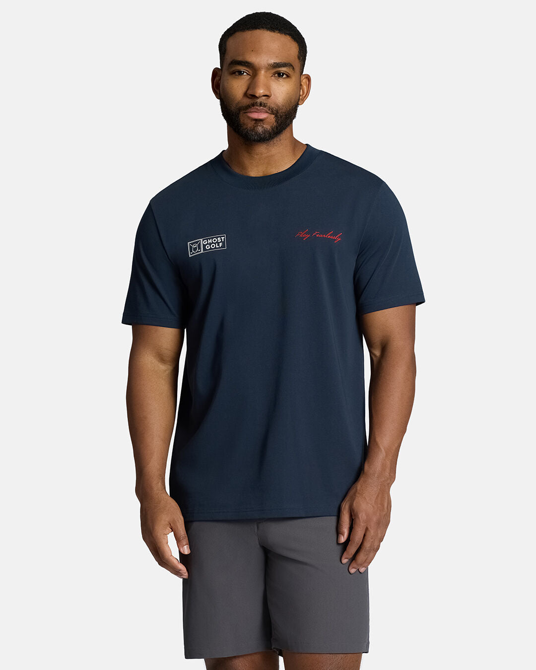Top Front Body Shot of Black Male Model Wearing Dark Navy Qualifier Player Tee show casing play fearlessly and ghost golf hit on each side of the chest. Play fearlessly on left and ghost golf on right. Model is wearing grey shorts #color_dark-navy