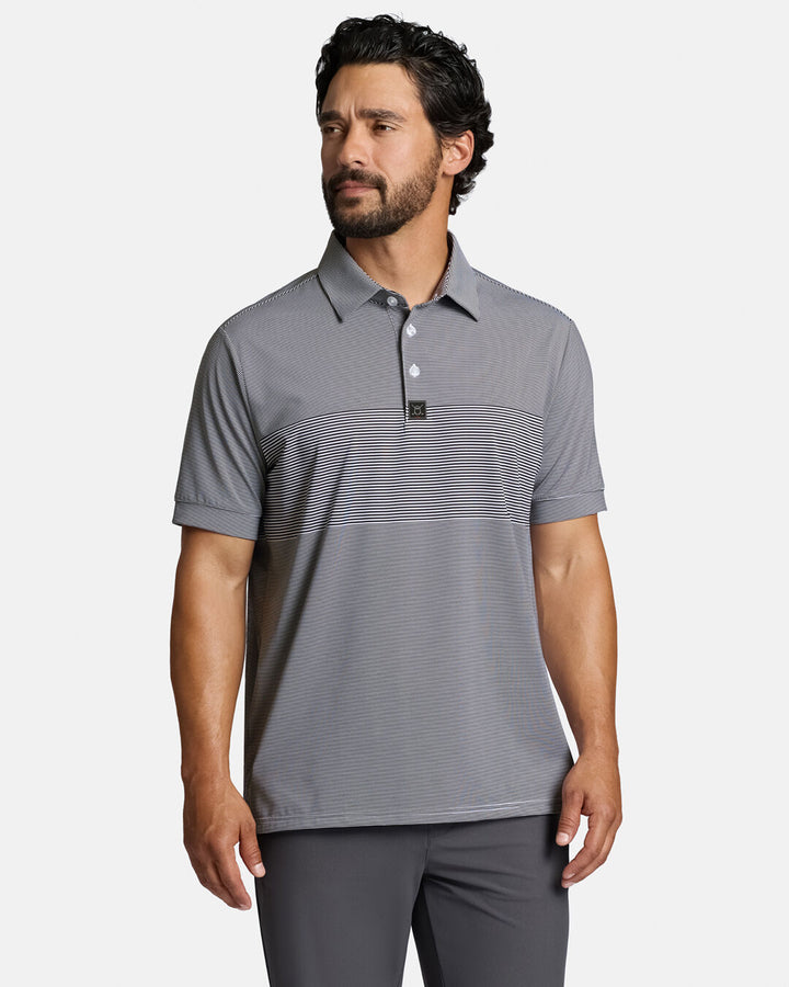 Top Front Body Shot of White Male Model Wearing Grey Qualifier Stripe Polo with grey pants. Polo is untucked #color_dark-navy
