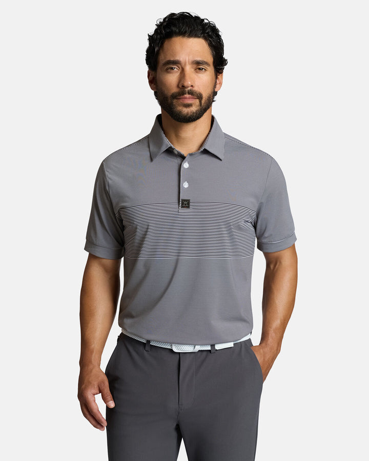 Top Front Body Shot of White Male Model Wearing Grey Qualifier Stripe Polo with grey pants and white belt. Polo is tucked #color_dark-navy