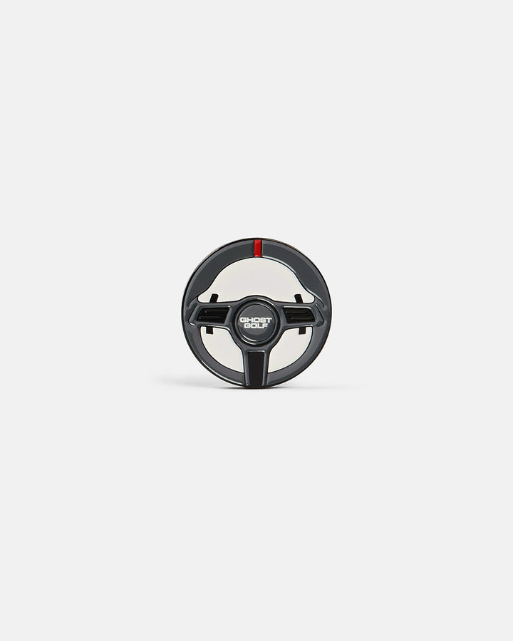 Product photo of a ball marker featuring a racing wheel design with the word “Ghost Golf.”