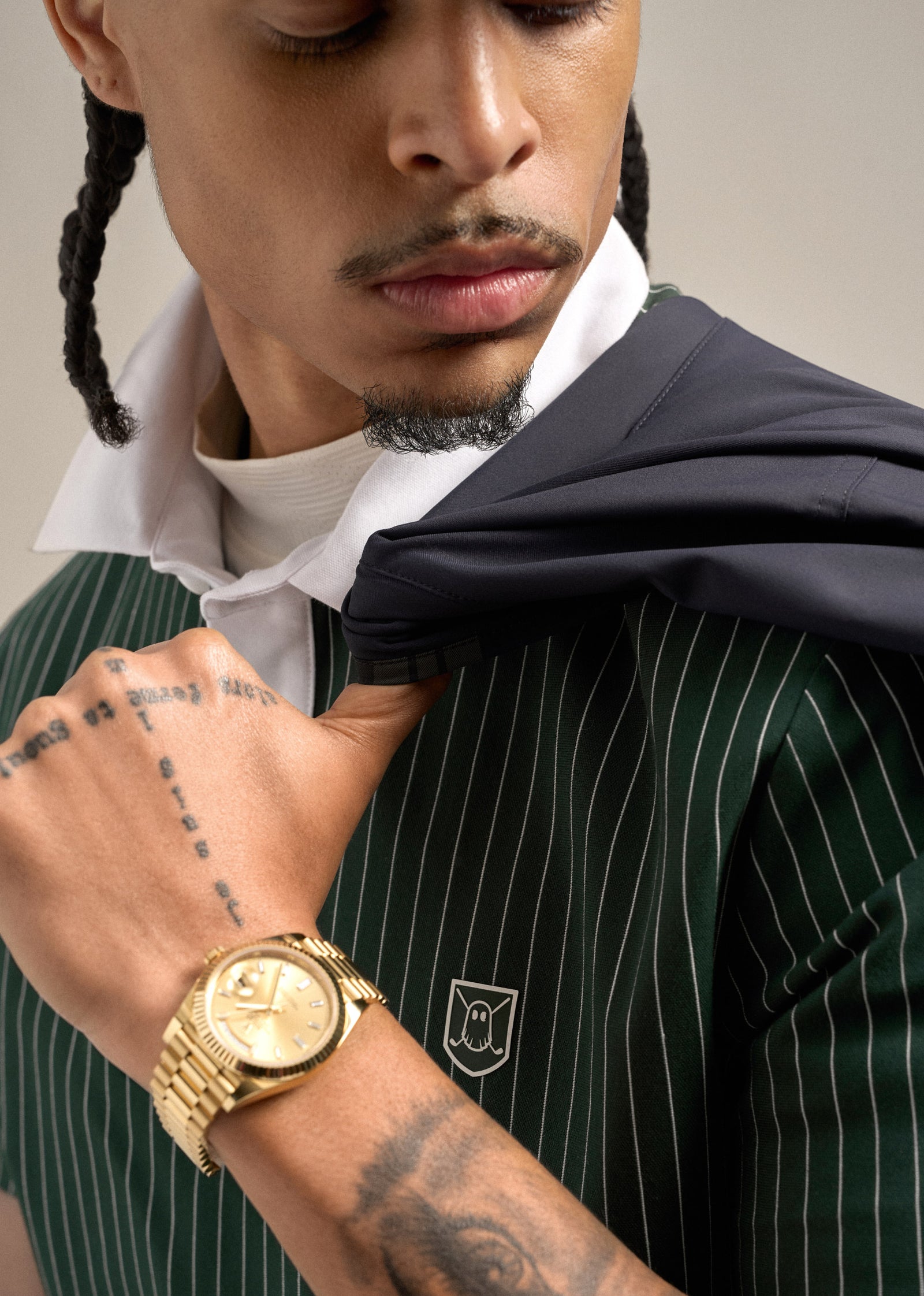 Close-up shot of a Black male model wearing a green polo and holding a jacket draped over his shoulder, creating a relaxed and polished look.