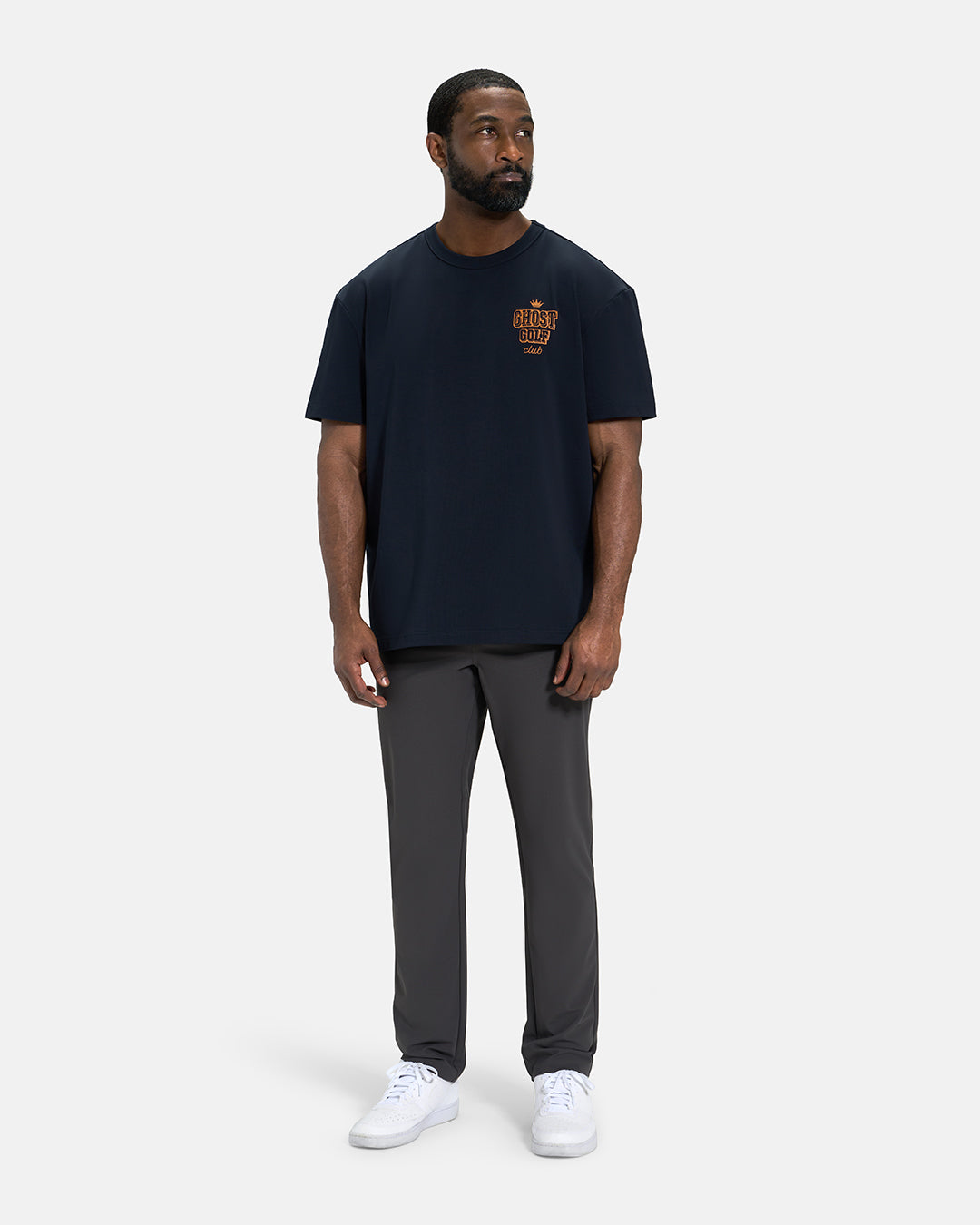 Full Body Front View of Navy Spectator Club Tee on Black Male Model wearing grey pants and white shoes #color_navy