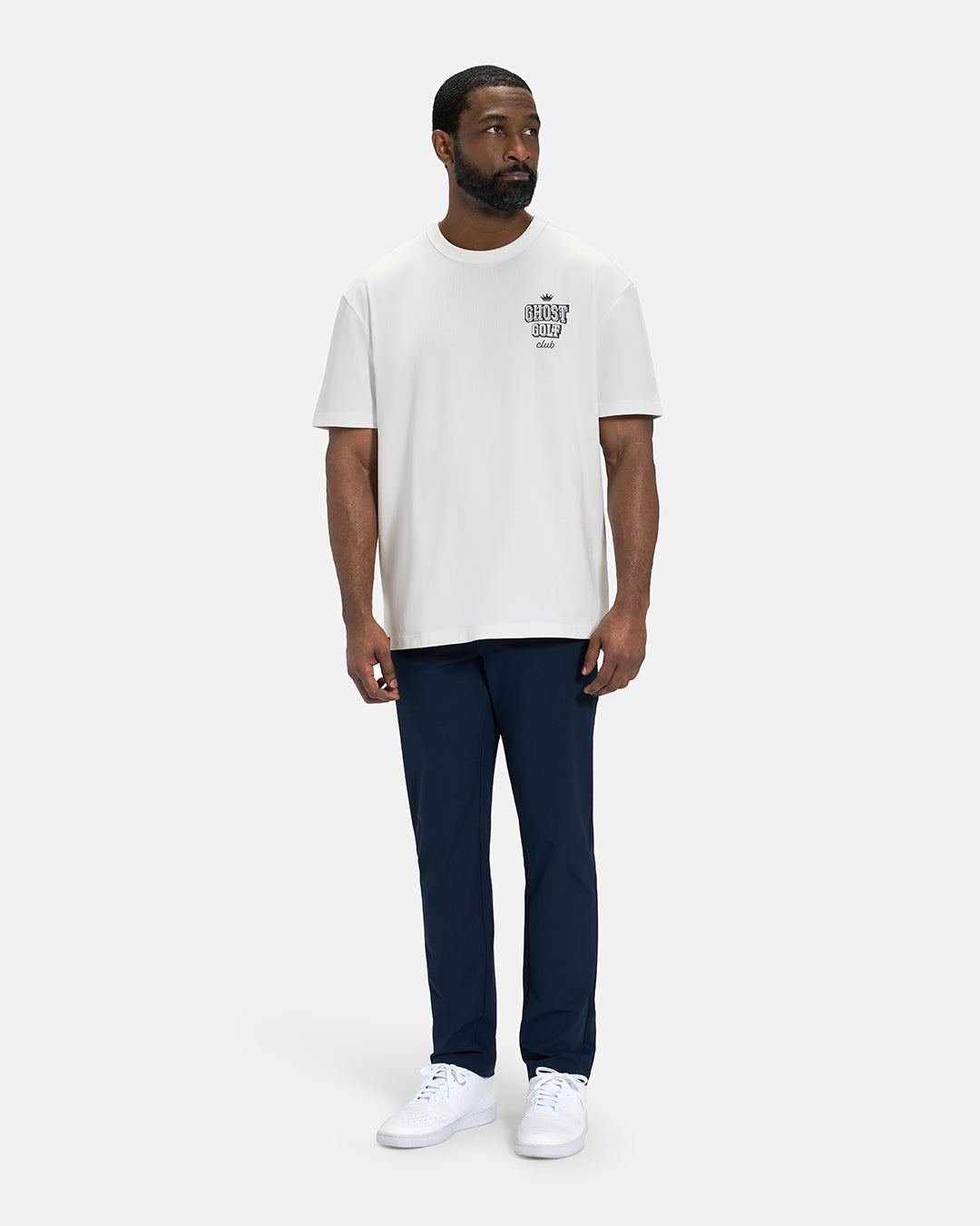 Full Body Front View of White Spectator Club Tee on Black Male Model wearing navy pants and white shoes #color_white