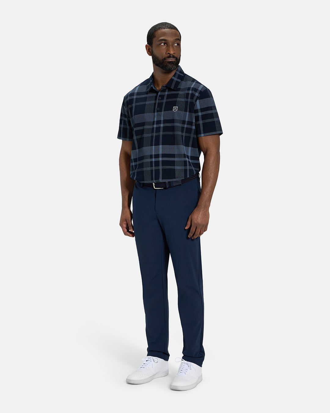 Full Body Front View of Navy Spectator Plaid Polo Tucked on Black Male Model wearing navy pants black belt and white shoes #color_navy
