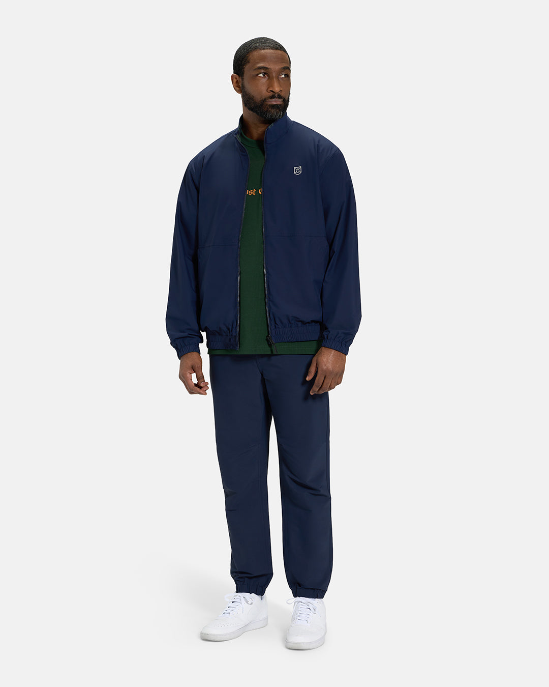 Full Body View of Plaid Dark Navy Spectator Reversible Jacket on Black Male Model wearing forest green tee navy joggers and white shoes #color_plaid-navy