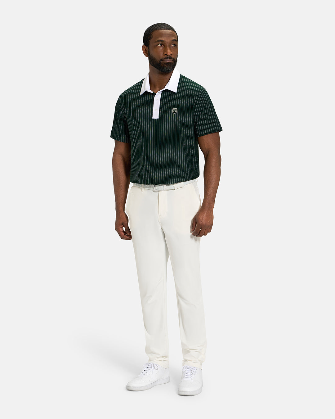 Full Body View of Bogey Green Spectator Stripe Polo Tucked on Black Male Model wearing white pants white belt and white shoes #color_bogey-green