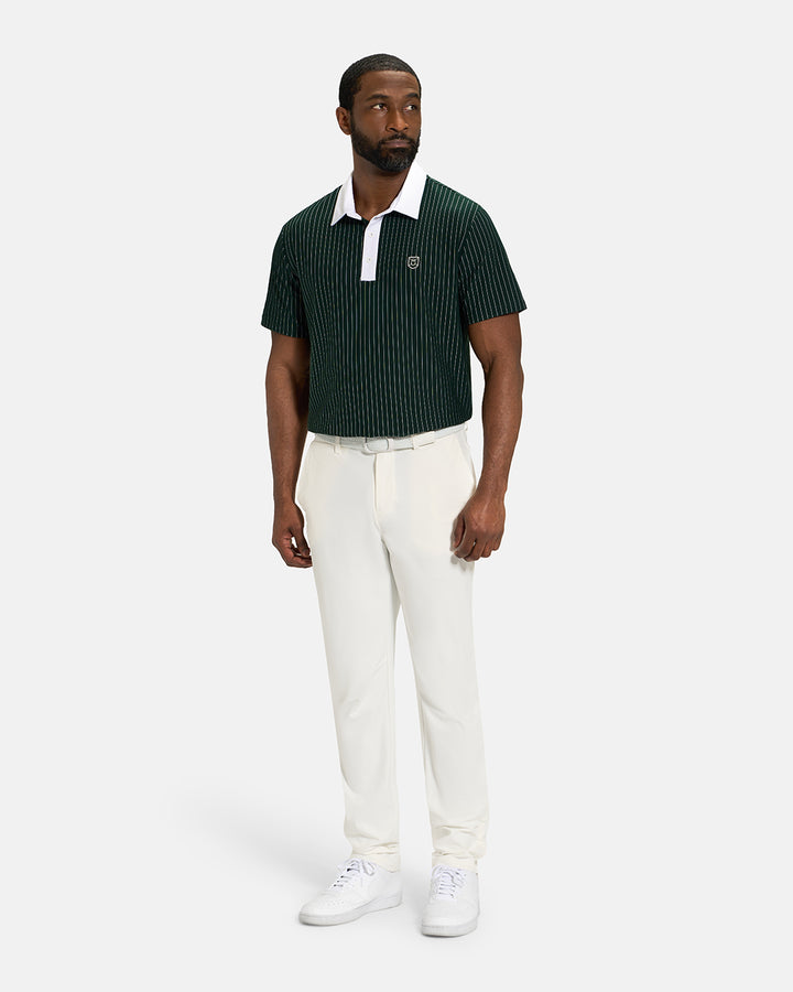 Full Body View of Bogey Green Spectator Stripe Polo Tucked on Black Male Model wearing white pants white belt and white shoes #color_bogey-green