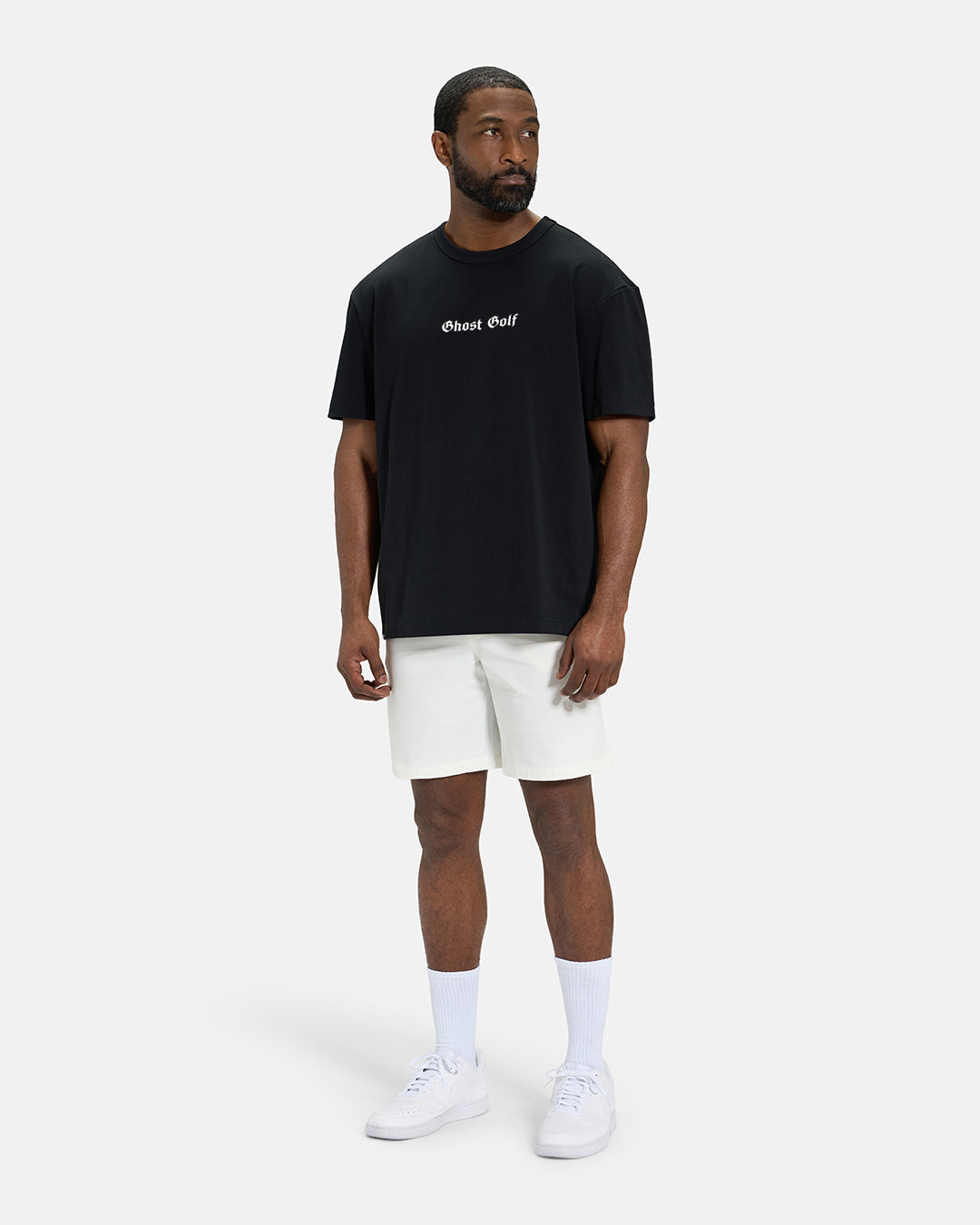 Full Body Front View of Black Spectator Tee on Black Male Model wearing white shorts and white shoes #color_black