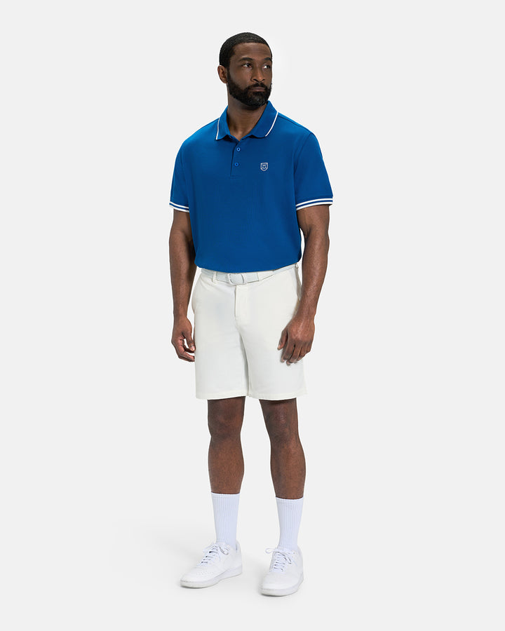 Full Body View of Royal Blue Spectator Tipped Collar Polo Tucked on Black Male Model wearing white shorts white belt and white shoes #color_royal-blue