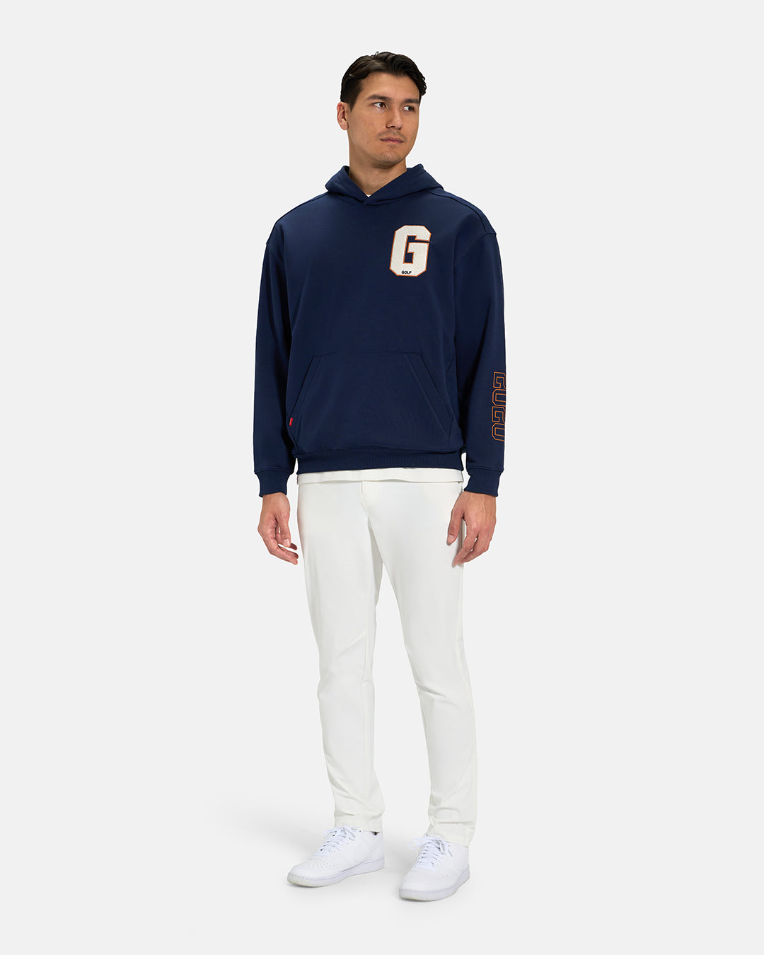 Full Body View of Navy Spectator Hoodie on Asian Male Model wearing white tee white pants and white shoes with letter G on chest #color_navy