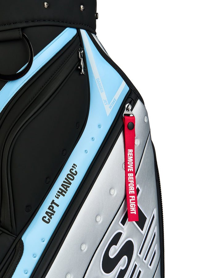 Detail shot of the Striker Staff Bag showcasing the signature red "Remove Before Flight" tab and Capt Havoc branding. Close-up image highlighting the premium materials, embroidered details, and aviation-inspired design elements.